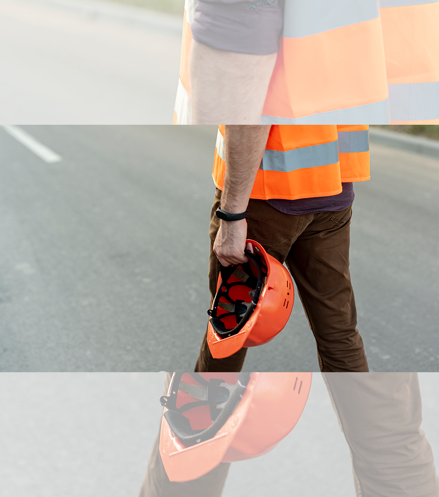 Homme avec gilet orange et casque de chantier qui marche sur une route